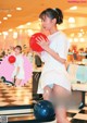 A woman holding a bowling ball in a bowling alley.