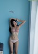 A woman in a pink lingerie leaning against a blue wall.