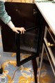 A woman is opening a cabinet with a glass door.