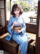 A woman in a blue kimono sitting on a wooden bench.