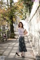 A woman walking down a sidewalk holding a purse.