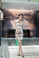 A woman in a cheongsam poses for a picture.