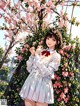 A girl standing in front of a tree with pink flowers.