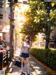 A woman walking down a street next to a tree.