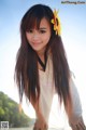 A woman with long brown hair and a sunflower in her hair.