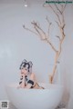 A woman sitting in a bathtub with a cat mask on.