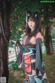 A woman in a kimono standing next to a tree.