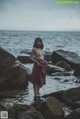 A naked woman standing in the water near some rocks.