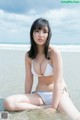 A woman in a white bikini sitting in the water.