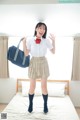 A woman in a school uniform holding a blue bag.