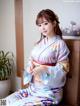 A woman in a kimono sitting on a wooden bench.