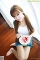 A woman sitting on the floor eating a slice of watermelon.